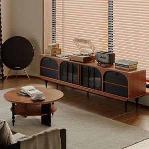 A modern living room features the Antique TV Cabinet Combo Set, displaying a turntable, radio, and books; a round coffee table with an open book sits nearby, while large window blinds fill the room with natural light.