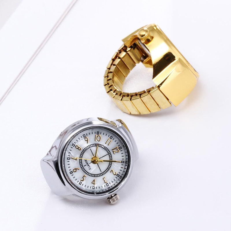 Two Vintage Ring Watch timepieces—one with a silver band, one gold—rest on a white surface. Both feature ring-shaped designs and classic analog faces, creating retro style with wearable charm.