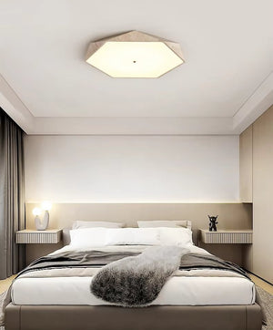 Modern bedroom with a neatly made bed, gray throw, two nightstands, table lamps, and the Natural Stone Ceiling Light overhead. Neutral tones and minimalistic decor create a clean, contemporary look that highlights the beauty of wabi-sabi lighting.