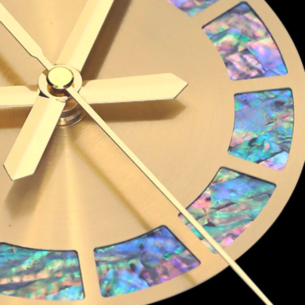 Close-up of the Premium Sun Wall Clock showcasing a gold face with Roman numerals crafted from iridescent blue abalone shell, plus visible gold hour, minute, and second hands.