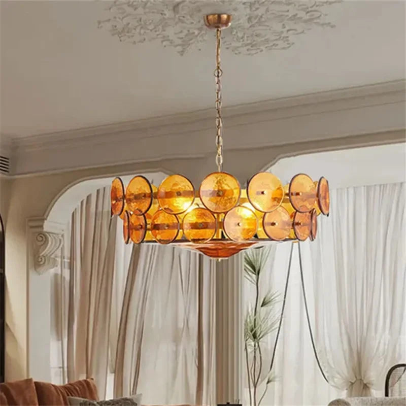 An Italian Retro Pendant Light with circular amber Murano glass discs hangs from the ceiling in a living room featuring beige curtains and arched decor.