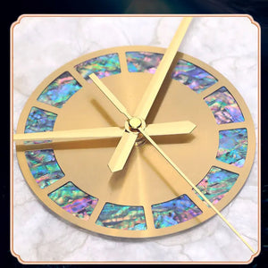The Premium Sun Wall Clock features a gold face with iridescent blue and green hour inlays, set on a sleek white marble surface for a sculptural look.