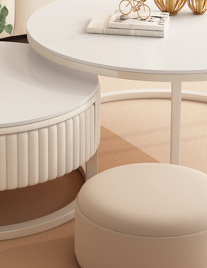 The Luxury Round Coffee Table Set, styled with books and decor, sits beside a textured side table and a beige ottoman atop a light carpet.