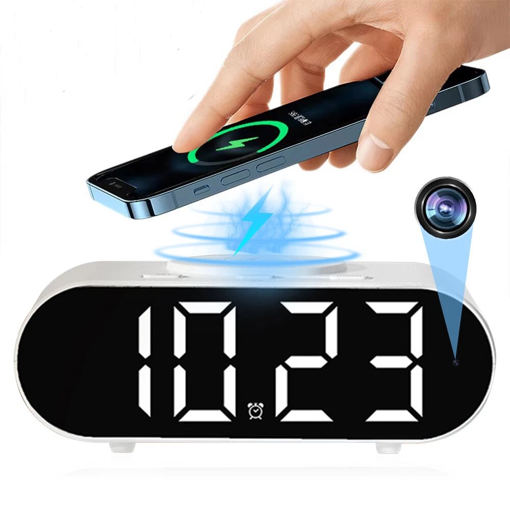 A hand sets a smartphone on the Digital Clock Charger SpyCam, which features wireless charging and a hidden camera lens graphic to the right. The clock shows 10:23.