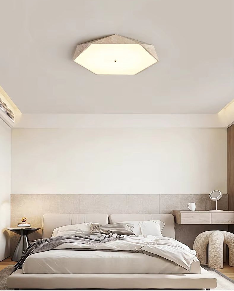 A modern bedroom features an unmade bed, wabi-sabi lighting design with the Natural Stone Ceiling Light, a small side table, and a vanity desk with a round mirror.