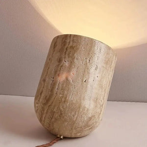 Aptly named the Natural Stone Lamp, this sculptural table lamp rests at an angle on a flat surface, its round form and stone-textured finish evoking the organic beauty of yellow cave stone. It casts a gentle, warm glow onto the wall and surrounding area, infusing any space with earthy elegance.