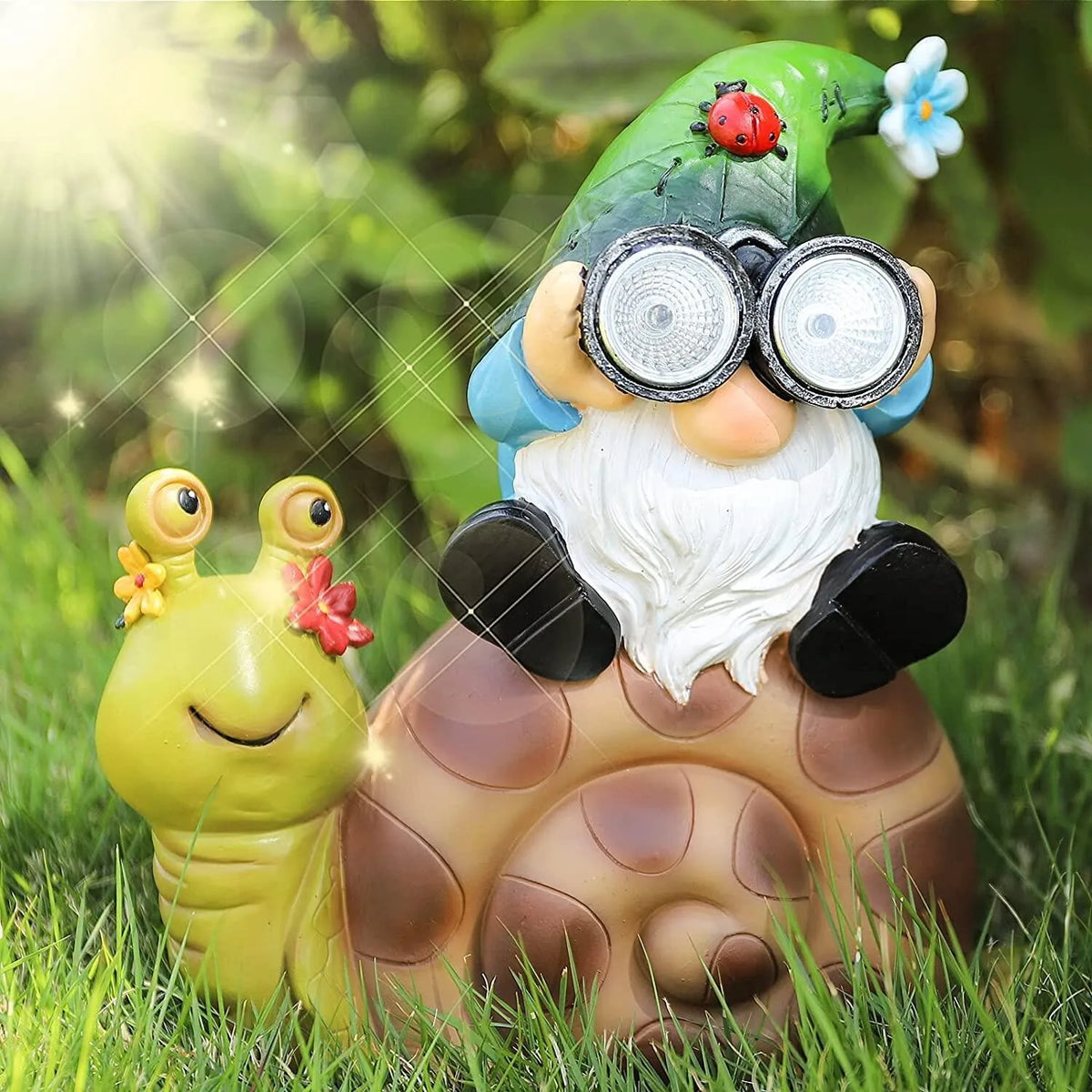 The Solar Gnome Snail Light features a garden gnome with large glasses perched atop a snail shell, accompanied by a cheerful yellow snail with a red flower, all nestled among vibrant green plants and bathed in sunlight—bringing whimsical charm and enchantment to your garden solar light collection.