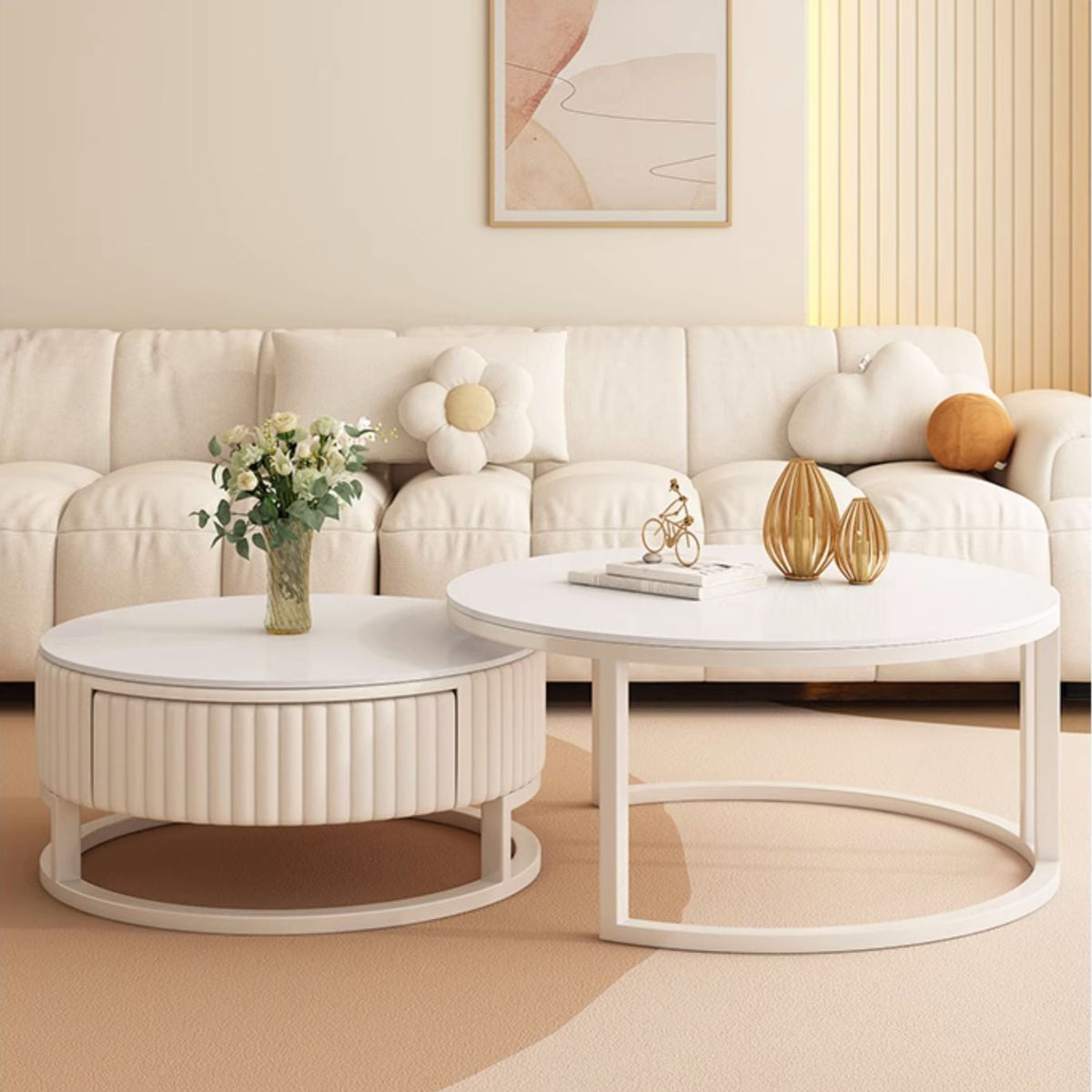 A modern living room with a cream-colored sofa, the Luxury Round Coffee Table Set, decorative vases, a flower bouquet, and abstract wall art.