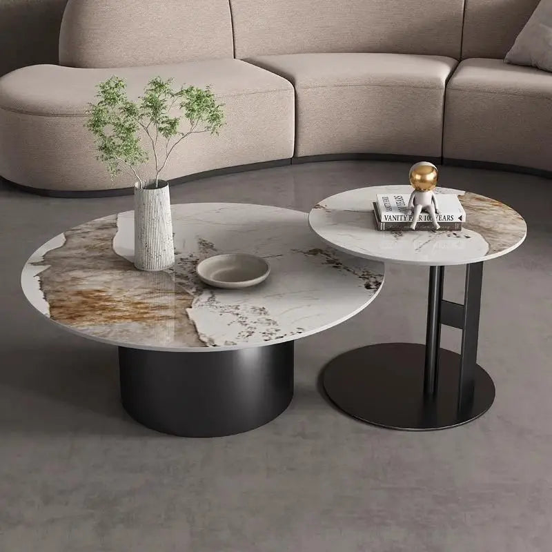 Two Premium Round Coffee Tables with marble tops are placed side by side; one features a vase with greenery and a dish, while the other displays stacked books and a gold accent piece.