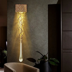 Introducing the Luxury Vertical Wall Light: a contemporary wall sconce featuring a textured rectangular shade, illuminated by glowing, intertwined branches, beautifully contrasting against a dark wall in a dimly lit room.