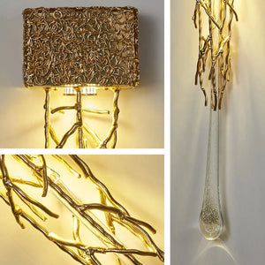 Close-up of the Luxury Vertical Wall Light, an ornate fixture with intricate gold, intertwined branch-like designs. This elegant sconce boasts hanging glass elements, all beautifully illuminated in warm tones.