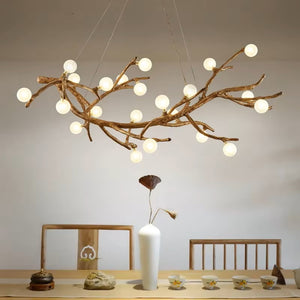 Above the dining table adorned with a vase, teapot, and cups, hangs the Branch Pendant Light. Its design mimics tree branches with glowing bulbs enclosed in glass orb shades, adding an organic modern touch to the cozy space.