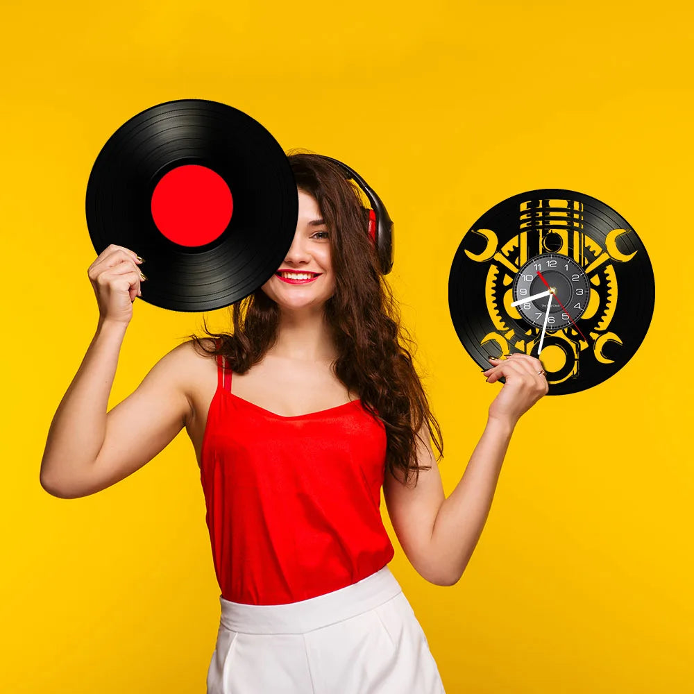 A woman in a red top holds a vinyl record and a Black Record Wall Clock against a vibrant yellow background.