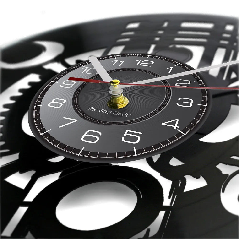 Close-up of a Black Record Wall Clock featuring white numbers and silver and red hands, with intricate gear designs in the background.