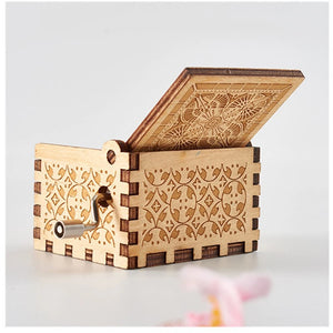 The Wooden Music Box, featuring intricate floral engravings and a hand-crank mechanism, is displayed with its lid partially open, playing classic tunes from its timeless wooden enclosure.