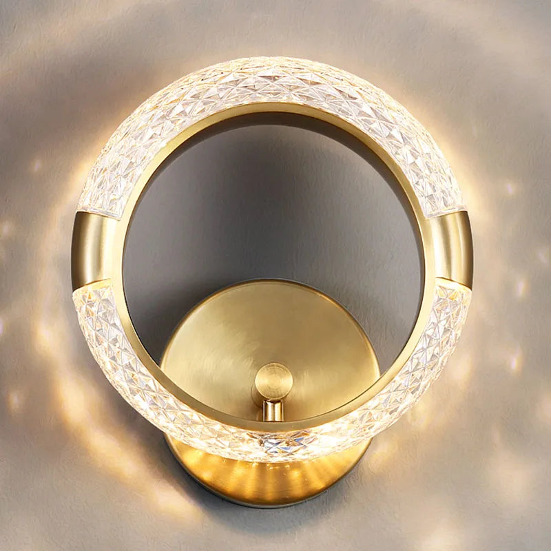 Elegant Ring Wall Sconce with a patterned glass ring, illuminated and mounted on a muted gray wall.