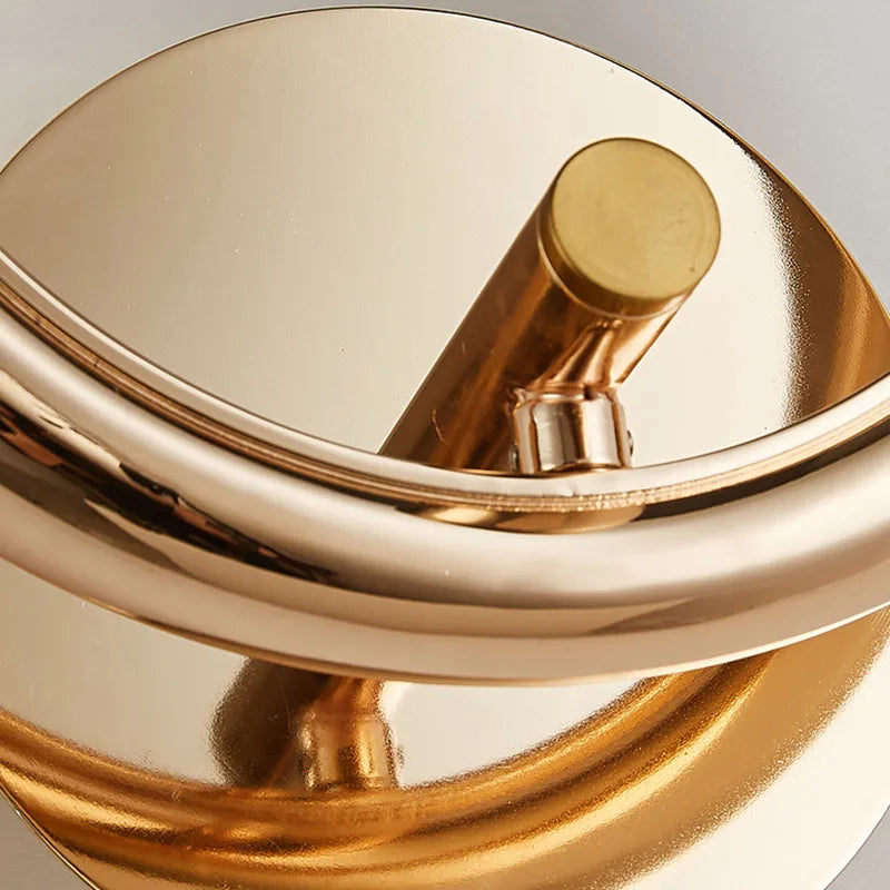 Close-up view of an Elegant Ring Wall Sconce, featuring a shiny gold finish with sleek curves and a cylindrical design, adorned with faceted crystals.
