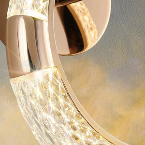 Close-up image of the Elegant Ring Wall Sconce, a modern luxury wall light featuring a gold finish and textured, illuminated glass design.