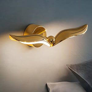A modern design wall light in the shape of a gold wing to mimic a bird flying in the sky, perfect for adding an artistic touch to any interior.