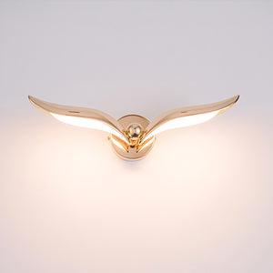 A modern gold wall light with a flying bird design.