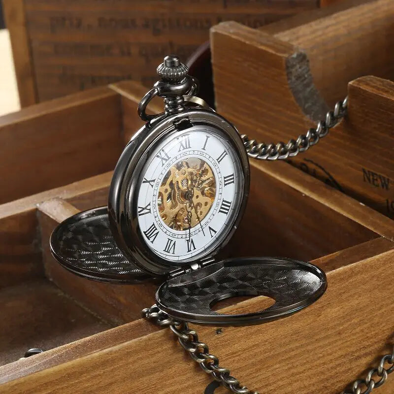 The Vintage Mechanical Pocket Watch, featuring Roman numerals and a visible movement, rests open on a wooden box and is attached to a metal chain.