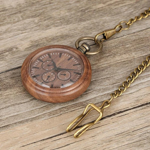 A Handmade Antique Vintage Pocket Watch, crafted from bronze and walnut wood with a quartz movement, features multiple small dials and a brass chain resting on a wooden surface.