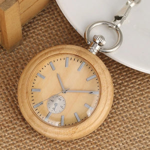 A Personalized Natural Minimalist Silver Bamboo Wood Pocket Watch Taschenuhr with a silver chain rests on burlap beside a white plate and wooden box, displaying the time 8:19:40.