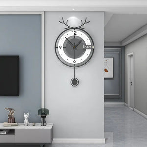 An Antler-like Wall Clock with a pendulum hangs on a white wall in a minimalist living room, seamlessly blending modern style with rustic charm.