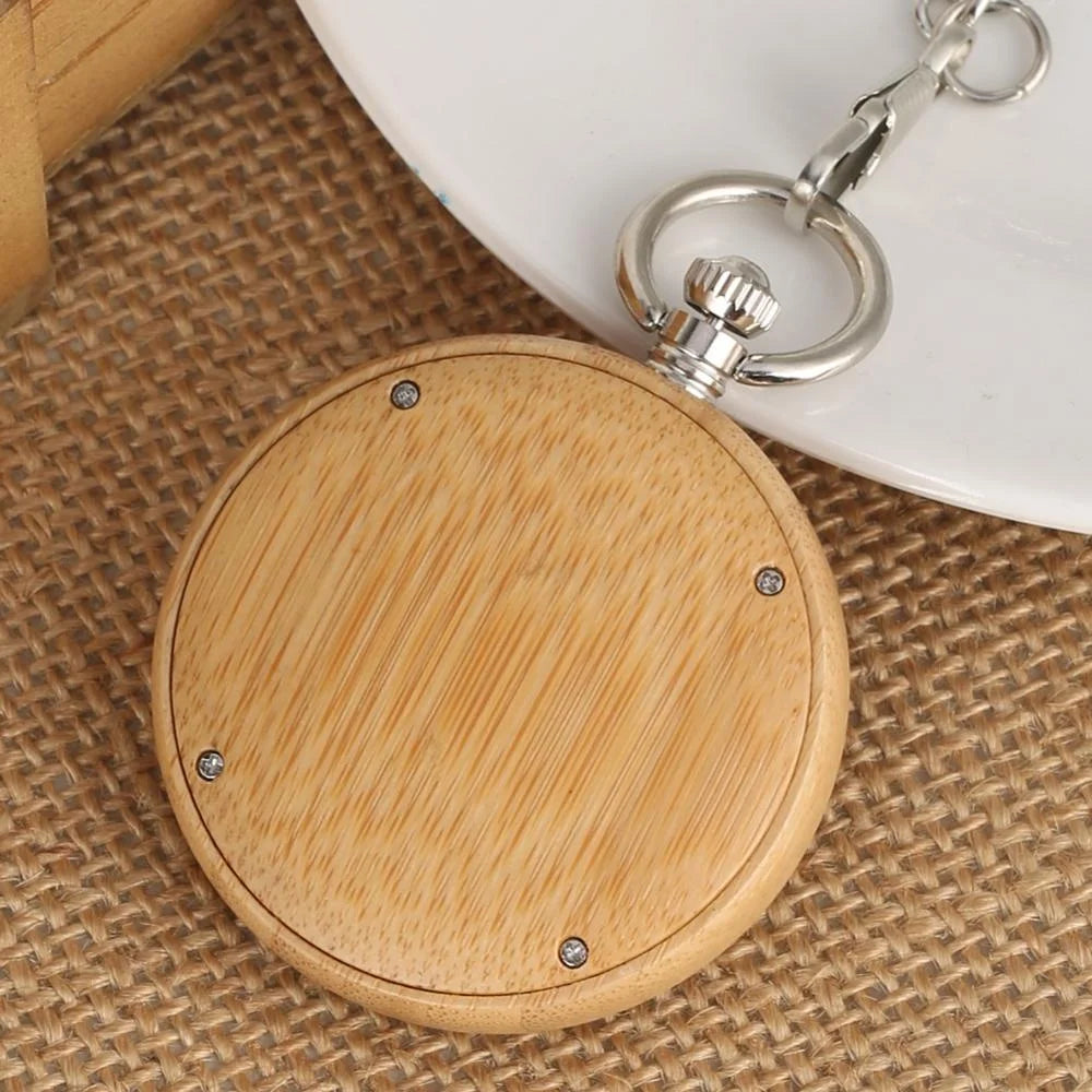 A Personalized Natural Minimalist Silver Bamboo Wood Pocket Watch Taschenuhr with a metal crown and clip rests on burlap fabric beside a white plate.
