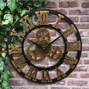 The Retro Gear Wall Clock, featuring Roman numerals and detailed gear motifs, is elegantly displayed on a brick wall amidst lush green leaves.