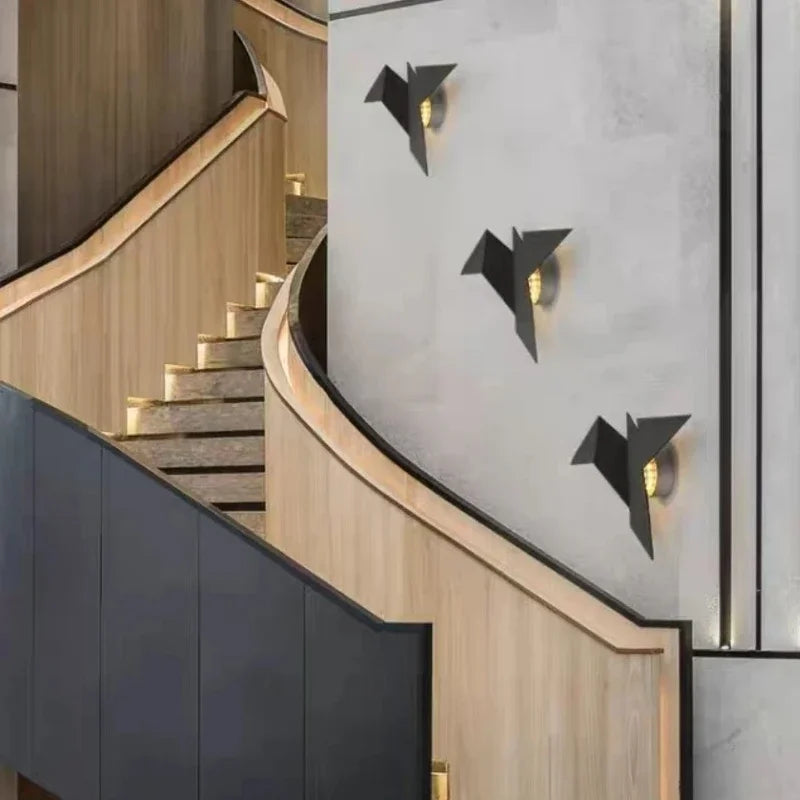Modern interior featuring a wooden staircase with black accents, and three wall-mounted Modern Flying Bird Wall Sconces.