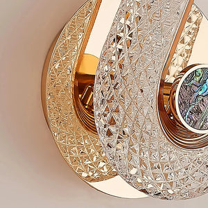 Close-up view of the Luxury Wall Sconce, a gold-plated and intricately patterned modern wall light featuring interwoven crystal elements and an abalone shell accent in its central circular feature, ideal for sophisticated indoor lighting.