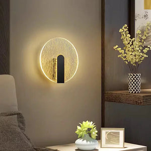 Beautiful Wall Sconce on a beige wall, next to a dark wooden shelf with a vase of yellow flowers and a small framed photograph. A green plant in a white vase is on a side table nearby, enhancing the minimalist design lighting.