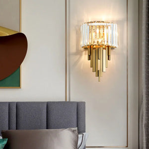 Luxury Geometric Wall Sconce featuring glass and metal accents, installed on a light-colored wall above a gray upholstered headboard.