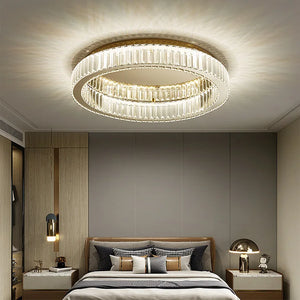 Modern bedroom featuring a Luxury Ceiling Circle Crystal Light, a gray accent wall, wooden furniture, table lamps, and neatly arranged pillows on the bed.