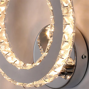 Close-up of a Crystal Dark Frame Wall Sconce with a sleek, modern circular design, featuring embedded crystals and emitting a warm white glow.