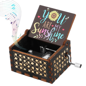 A decorative, hand-crank music box from the "You Are My Sunshine" collection, featuring a wooden build and an inscription of the song's title on the inside of the open lid. Musical notes seem to float out from the box, adding an enchanting touch.