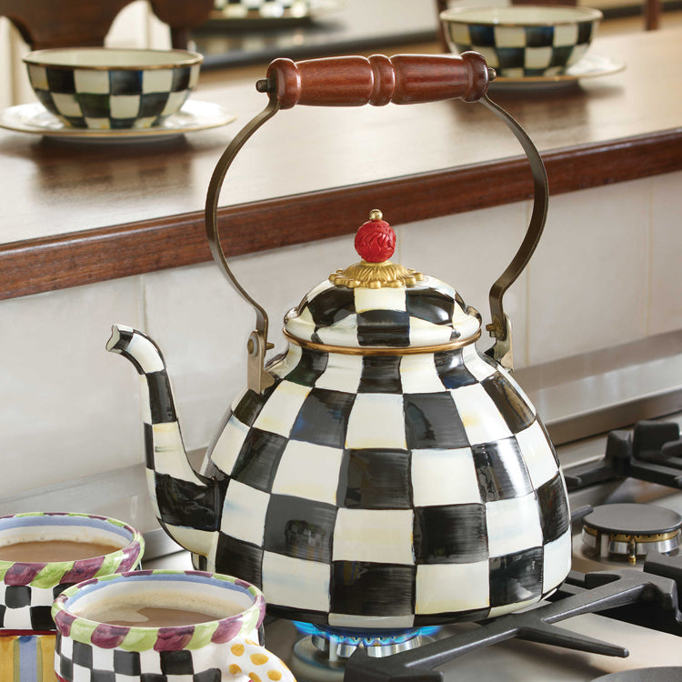 The Vintage Black and White Kettle with a sparrow-shaped knob sits on a stove, surrounded by matching checkered bowls and cups.