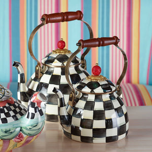 Two Vintage Black and White Kettles with wooden handles and red knobs sit on a table in front of a colorful striped background.