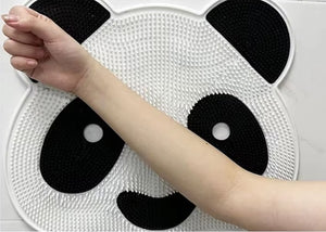 A hand reaches over a Panda Shower Massage Mat, showcasing its textured surface with a black and white design, ideal for foot massage to enhance circulation.