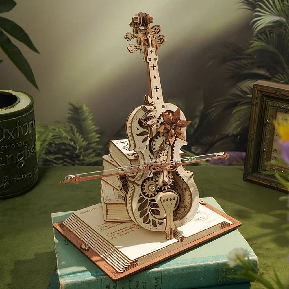 A detailed 3D wooden puzzle of the Cello Puzzle Music Box, featuring gears and intricate carvings, displayed on an open book and surrounded by greenery and some books.