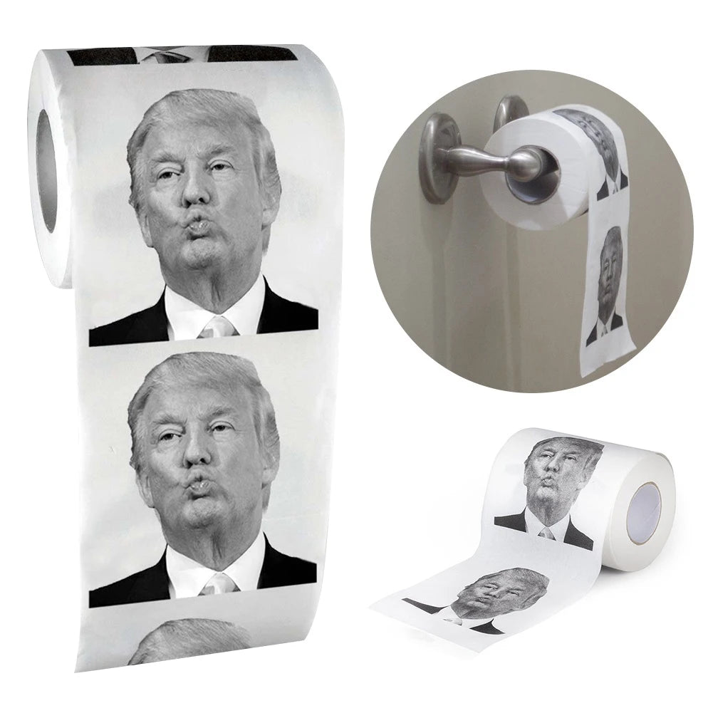 Trump Toilet Paper features repeated black-and-white images of Trump's face, displayed both on a holder and unrolled flat.
