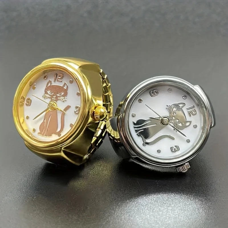 Two Cat Ring Watches are displayed on a dark surface: one gold with a brown cat design, and one silver with a black cat design—stylish timepieces that showcase feline elegance.