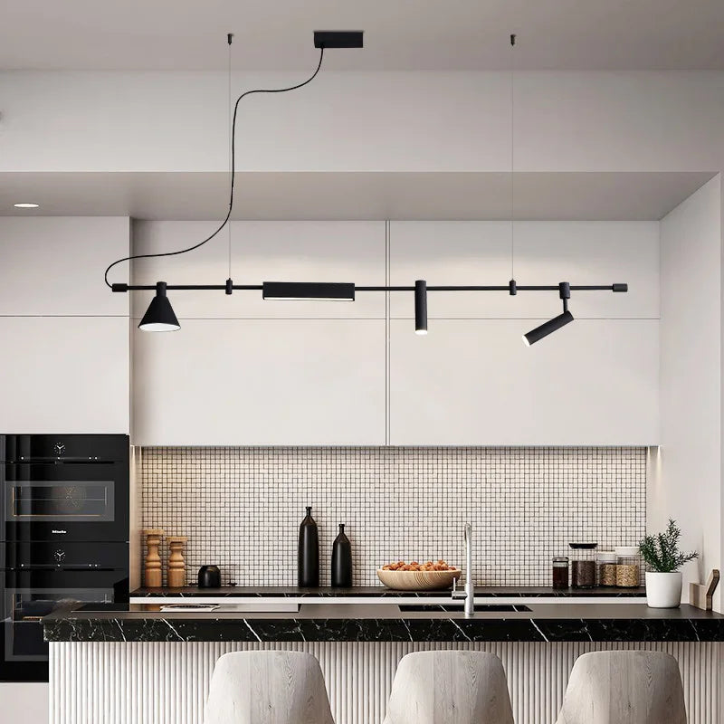 A modern kitchen with black and white decor features a Mosaic Tile Backsplash, a Black Countertop, and Modern Track Lighting. In front of the counter are two white stools.