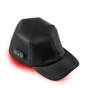 Man wearing heated cap for hair growth with red light glowing under the black baseball cap brim and side control buttons visible.