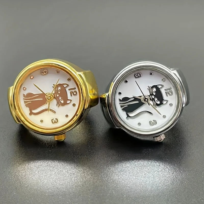 Two Cat Ring Watches—a gold one with a brown cat face and a silver one with a black cat face—are displayed side by side on a dark surface, making them perfect accessories for any feline jewelry lover.