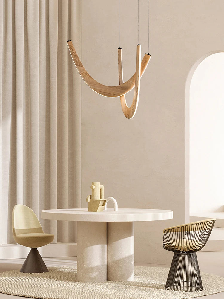 Minimalist dining area featuring a round table, two modern chairs in neutral tones, a textured rug, soft natural light, and the Double Curve Wood Pendant Light for added warmth and elegance.