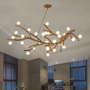 The Branch Pendant Light, with its modern design and glass orb shades resembling tree branches, brightens a living room with large windows and an office desk.