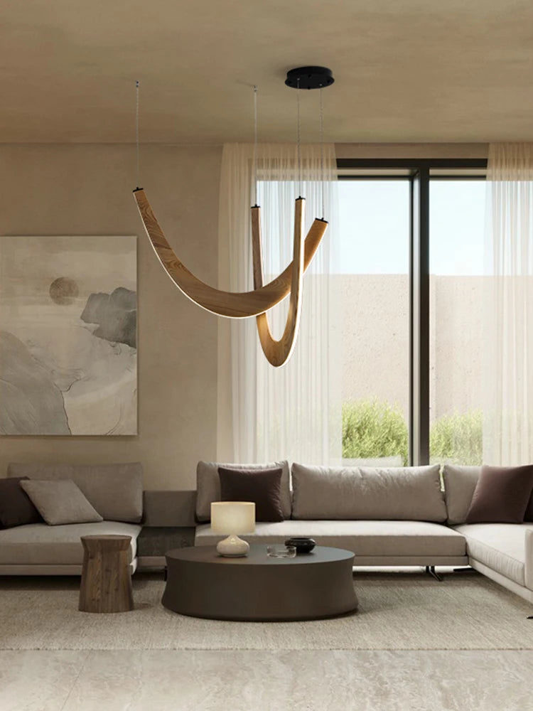 A modern living room with neutral tones, featuring the Double Curve Wood Pendant Light, a round coffee table, two sofas, sheer curtains, and abstract wall art.