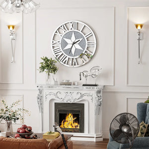 A white ornate fireplace with a fire burns beneath the Astral Chic Roman Wall Clock, which features an open-frame design and a striking crushed glass center, in a cozy living room decorated with plants and glassware.
